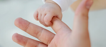 طفل يمسك بإصبع أمّه