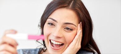 امرأة تبتسم تحمل جهاز فحص الحمل