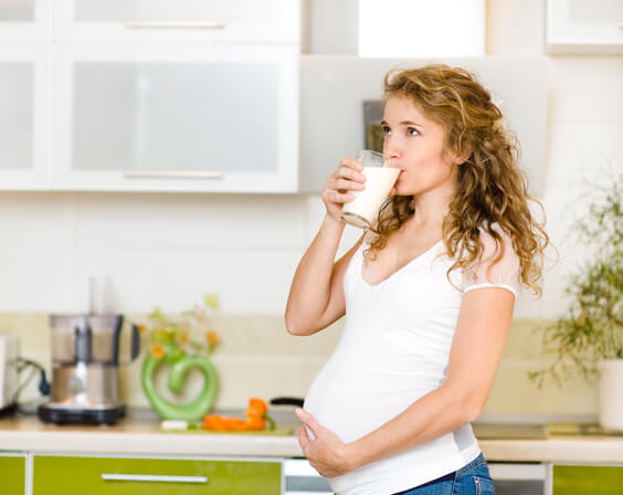 امرأة حامل تمسك كأس حليب