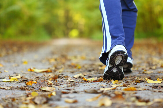 أقدام امرأة تلبس حذاء رياضة أثناء المشي في الغابة