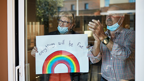 A couple with a rainbow picture clapping in support of medical professionals.