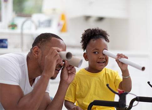 A father and his daughter look through homemade binoculars.