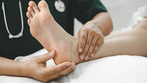 Healthcare professional holding patient’s ankle and applying light pressure to patient’s heel.
