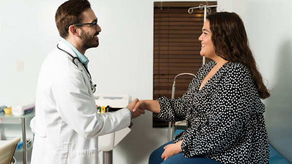Male doctor warmly greets female patient.