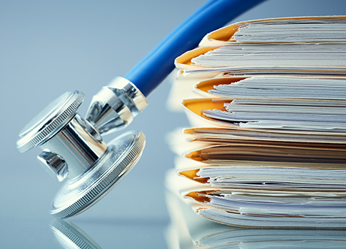 A blue stethoscope next to a stack of medical documents