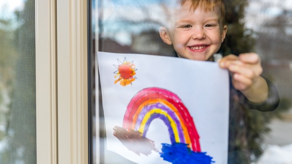 Child holds rainbow painting against window