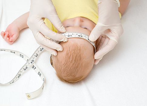 A doctor measuring the head circumference of a baby