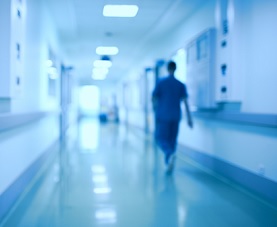 Silhouette of physician walking down dimly-lit hospital hallway