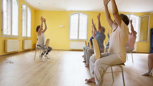 Group of older adults exercise while sitting in chairs