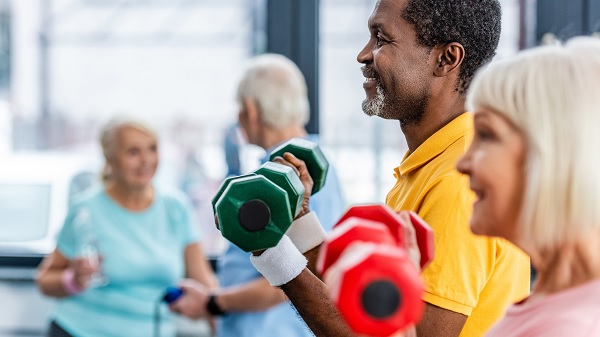 A group of older adults lift colorful hand weights