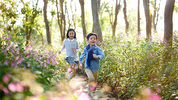 Two children running down a path through nature.
