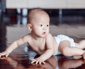 A diaper-clad baby crawls on a hardwood floor.