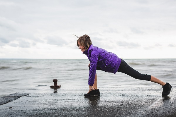 Female runner stretches on an ocean-side dock