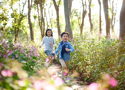 Two children running down a path through nature.