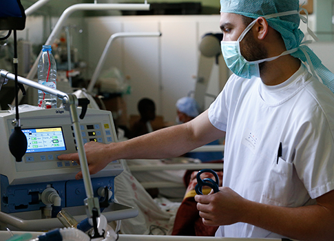 A respiratory therapist adjusts ventilator settings