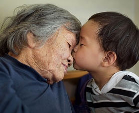 A little boy kisses his grandmother on the forehead  
