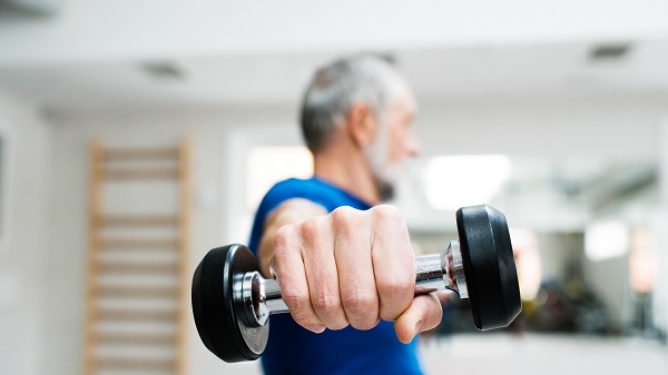 Older man holds hand weights toward camera