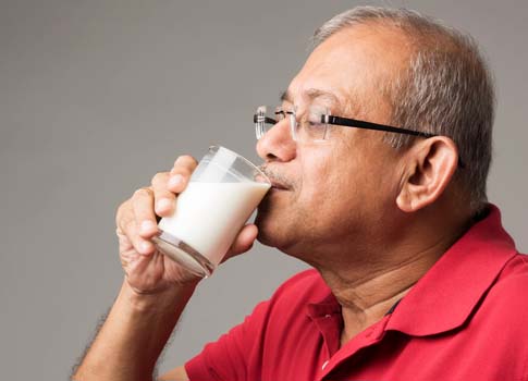 A man sips a glass of milk.
