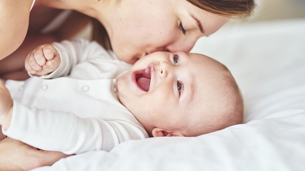 A mom kissing her laughing baby on the cheek