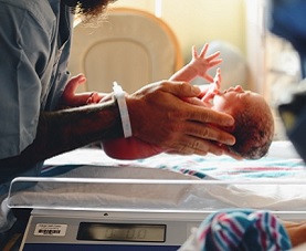 Nurse holds preterm infant in palms of her hands