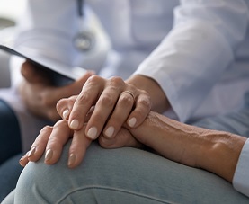 A closeup of a nurse's hand placed over her patient's hand