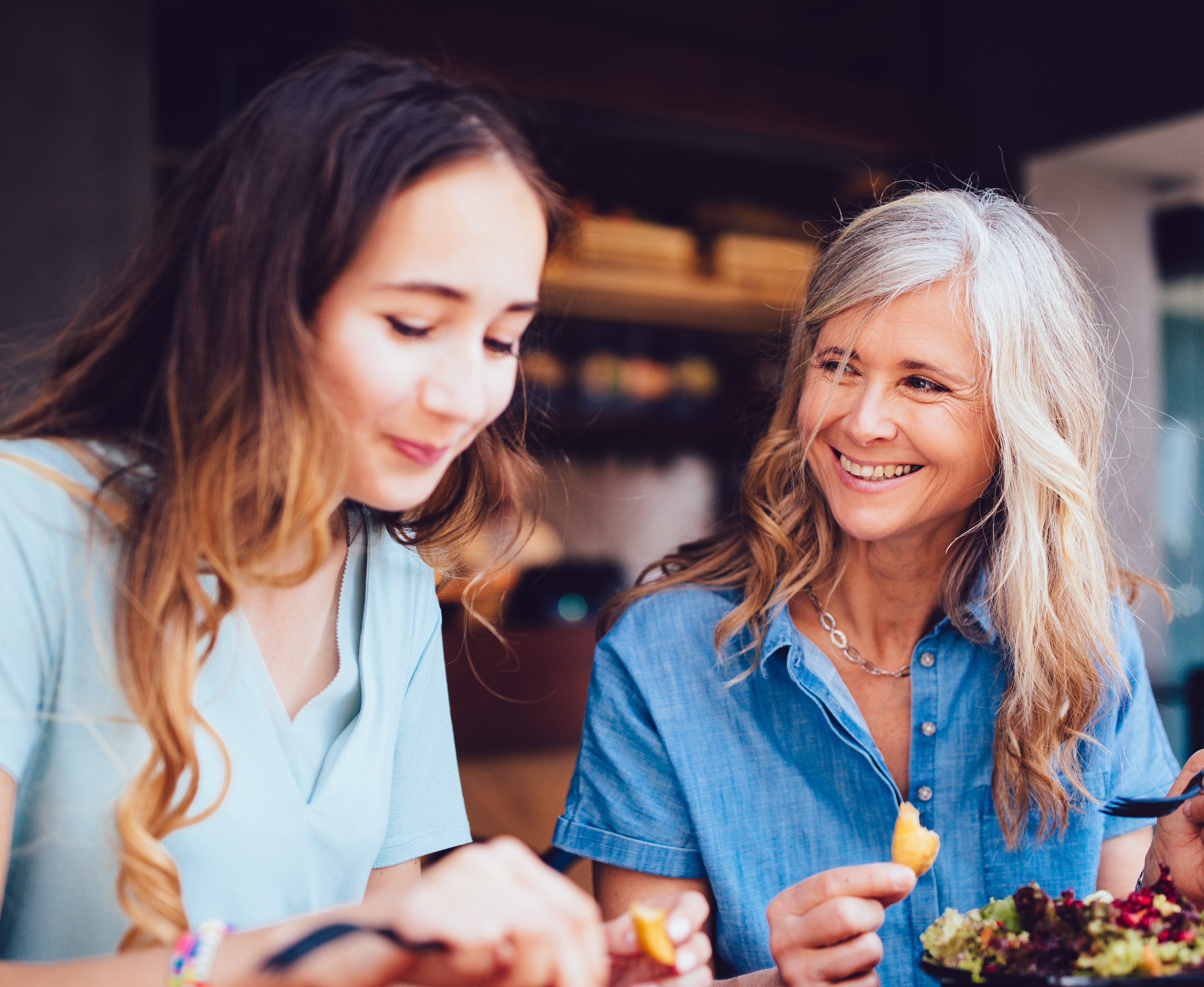 A young woman and an older woman eating brunch and smiling