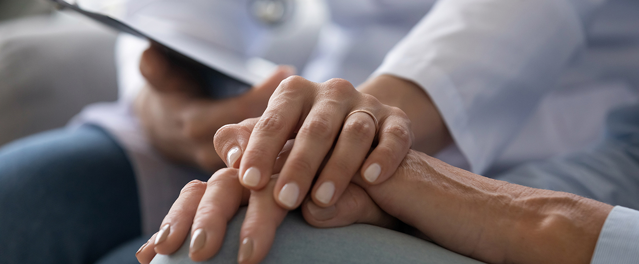 A doctor holding the hand of an adult patient 