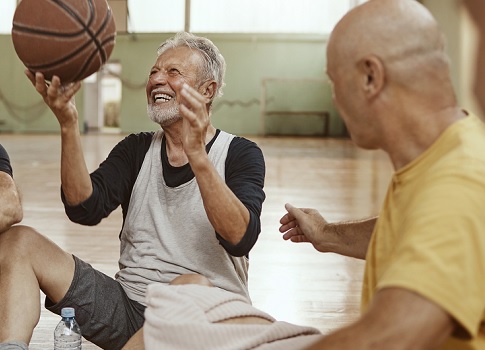 Group of older guys sit on gymnasium floor after playing basketball