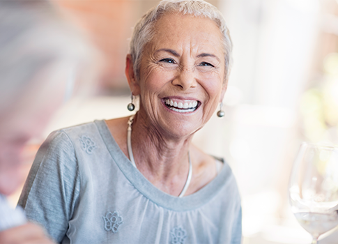 An older woman smiles while talking with friends.