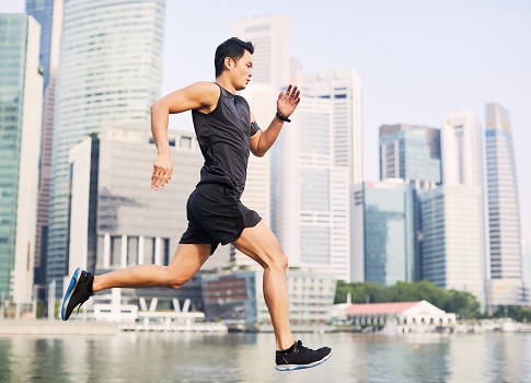 Young man running through Singapore cityscape