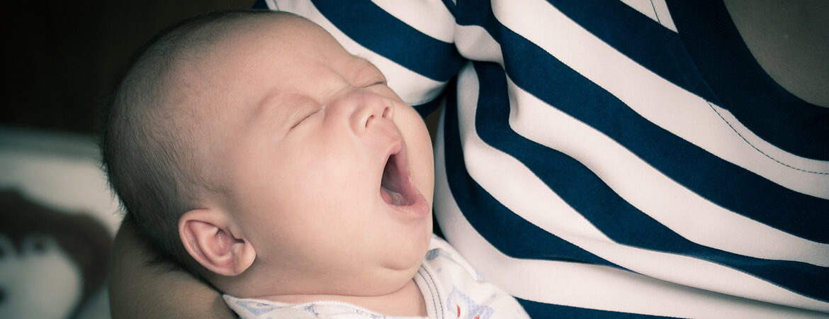 طفل نائم يتثاءب في حضن أمه
