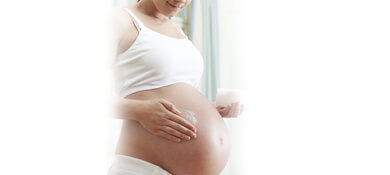 امرأة حامل تضع كريم ترطيب على بطنها