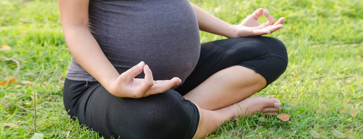 امرأة حامل تمارس اليوغا على العشب