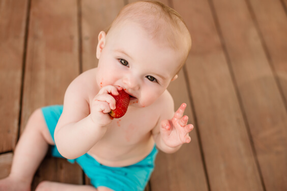 طفل يأكل حبة من التوت الأرضي