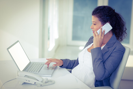 امرأة تجلس أمام الحاسوب وتتحدث في الهاتف 