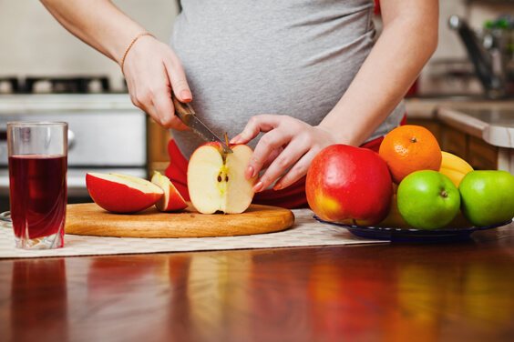 امرأة حامل تقطع فاكهة