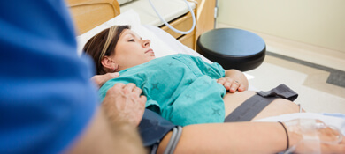 امرأة حامل في المستشفى وزوجها يقف إلى جانب سريرها ويمسك بيدها