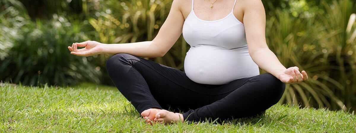 امرأة حامل تمارس اليوجا على العشب