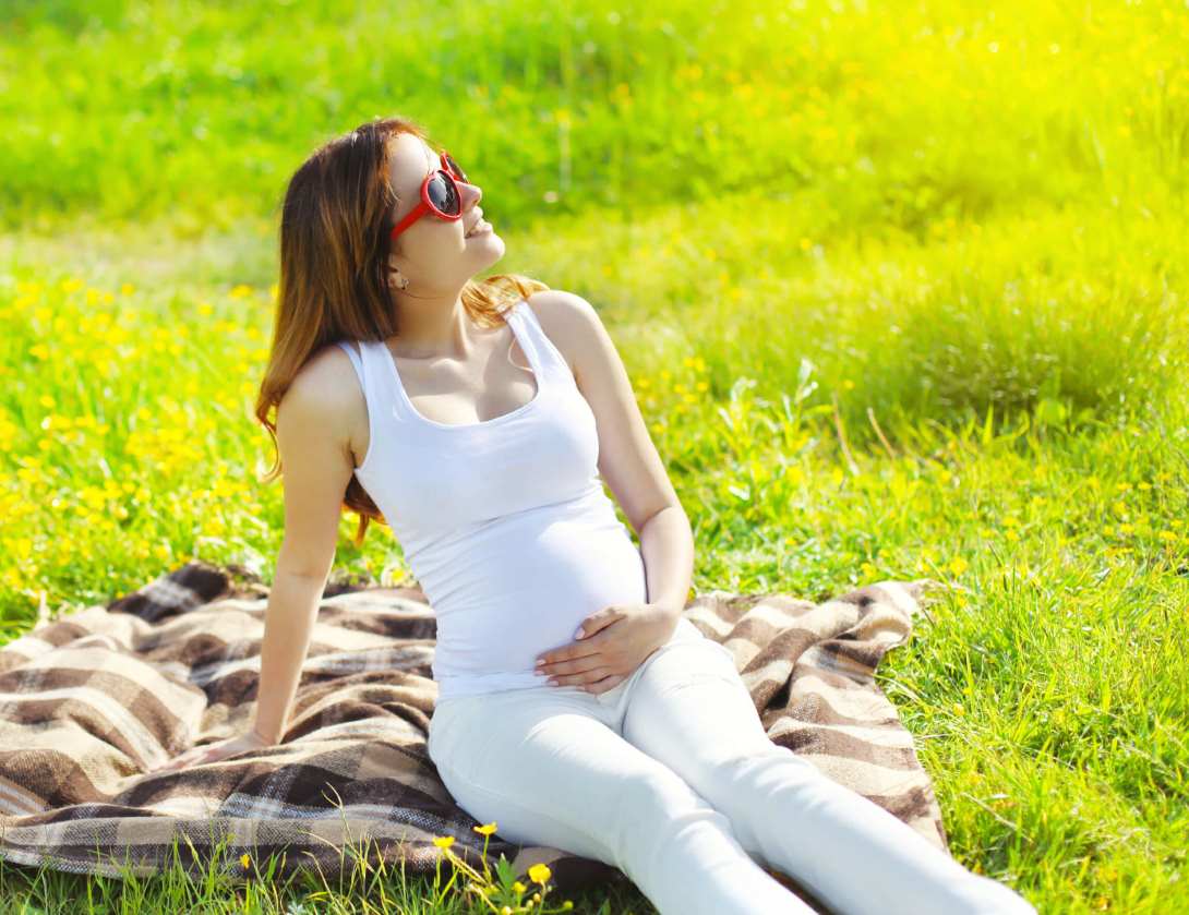حامل تضع النظارات الشمسية وتجلس على العشب في الحقل