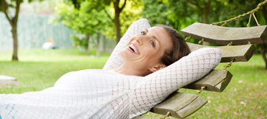 امرأة شابة مبتسمة مستلقية على أرجوحة في الحديقة
