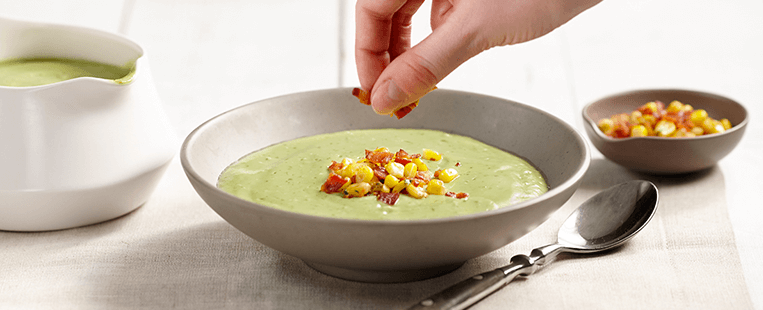 Avocado soup made with Ensure® Regular garnished with corn and bacon