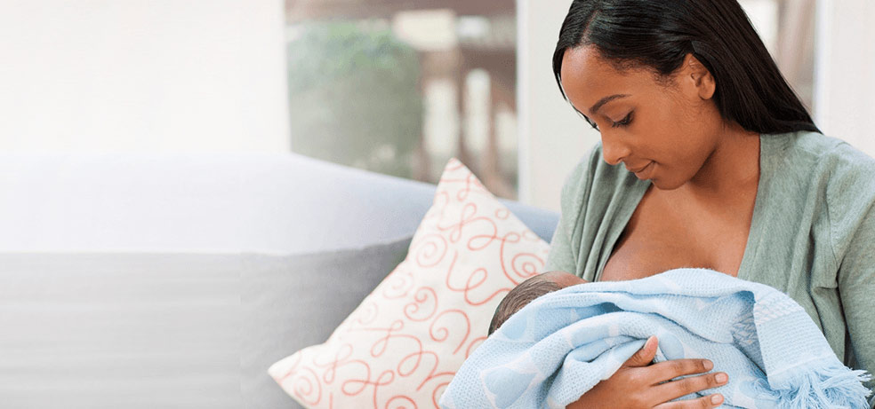 A black mother nursing her first year baby with her breast