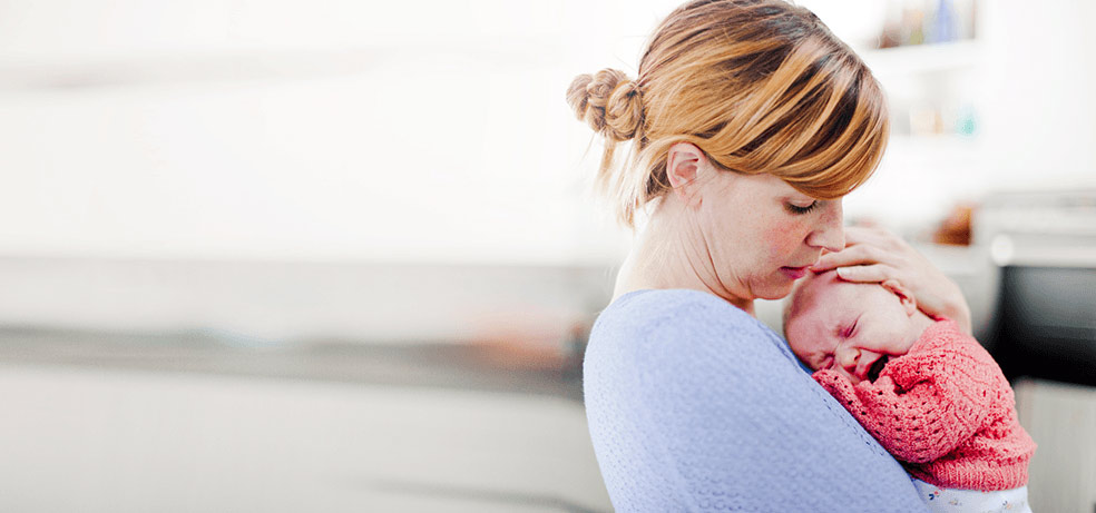 A infant crying excessively while her worried mother holds him