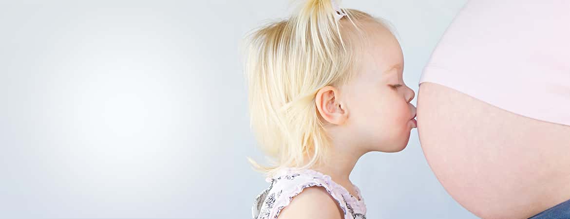 ילדה קטנה מנשקת את בטן הריונית