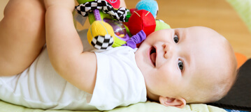 תינוק שוכב על הגב ומשחק עם צעצוע