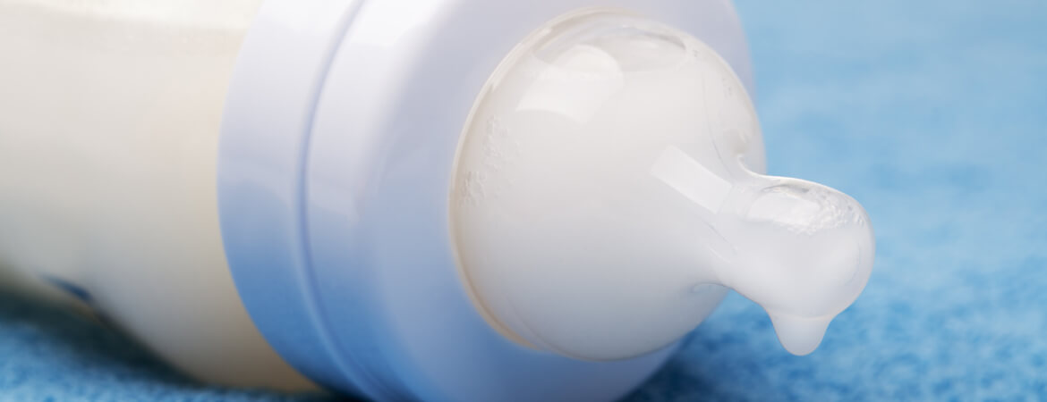 בקבוק חלב של תינוק שוכב על רקע כחול