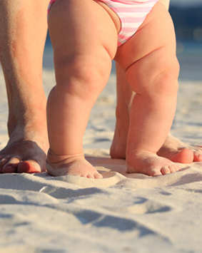קלוזאפ על רגליים של אמא ותינוק על שפת הים