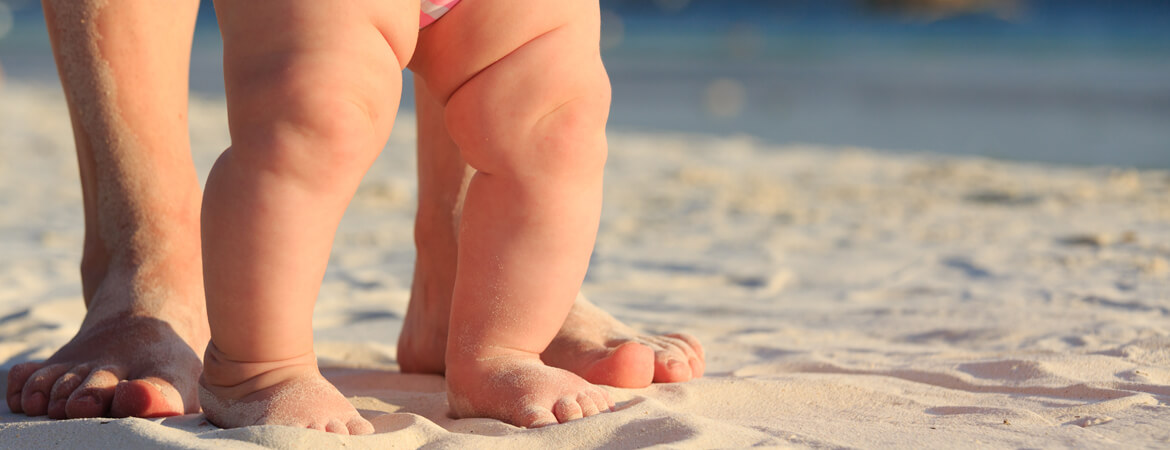 קלוזאפ על רגליים של אמא ותינוק על שפת הים