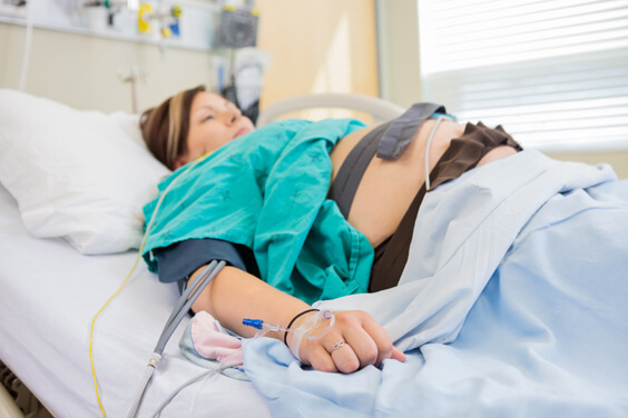 אישה בהריון שוכבת בבית החולים עם מנטר צירים על הבטן