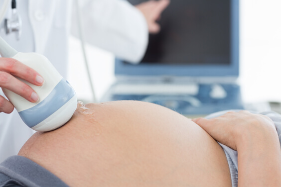 קלוז אפ לבטן של אישה בהריון עוברת בדיקת אולטרסאונד